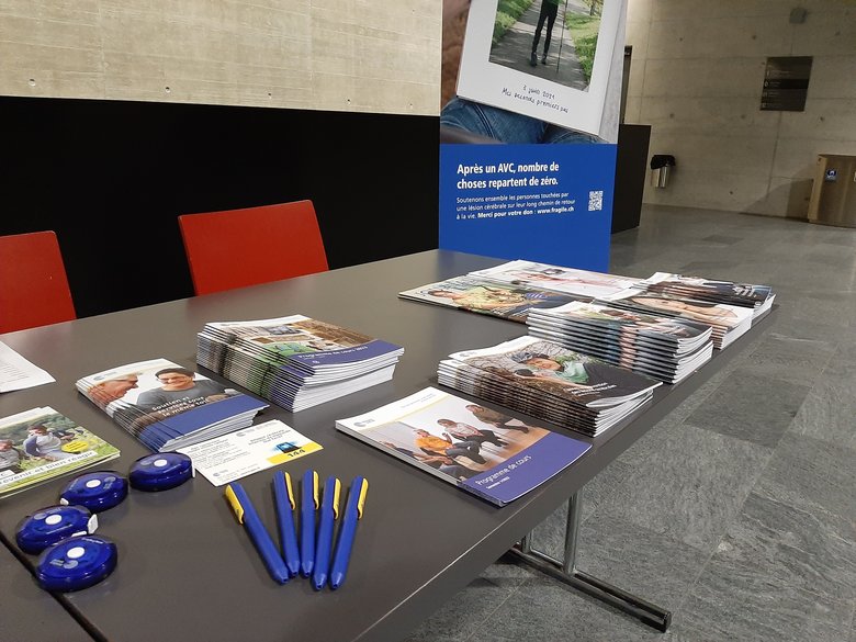 Stand d'information avec différentes brochures. Un roll-up est à l'arrière-plan