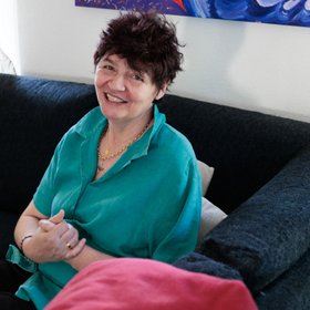 Une femme vêtue d'une blouse bleue assise sur un canapé