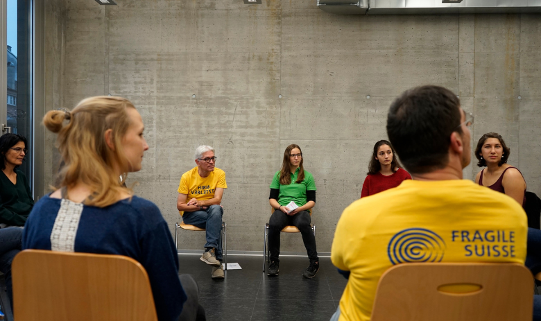 Eine Gruppe Menschen sitzt im Kreis und tauscht sich aus.