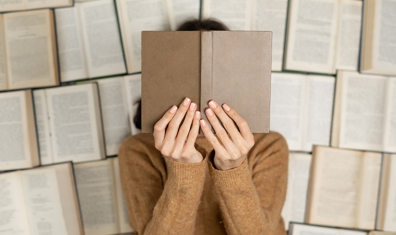 Une femme tient un livre ouvert devant son visage